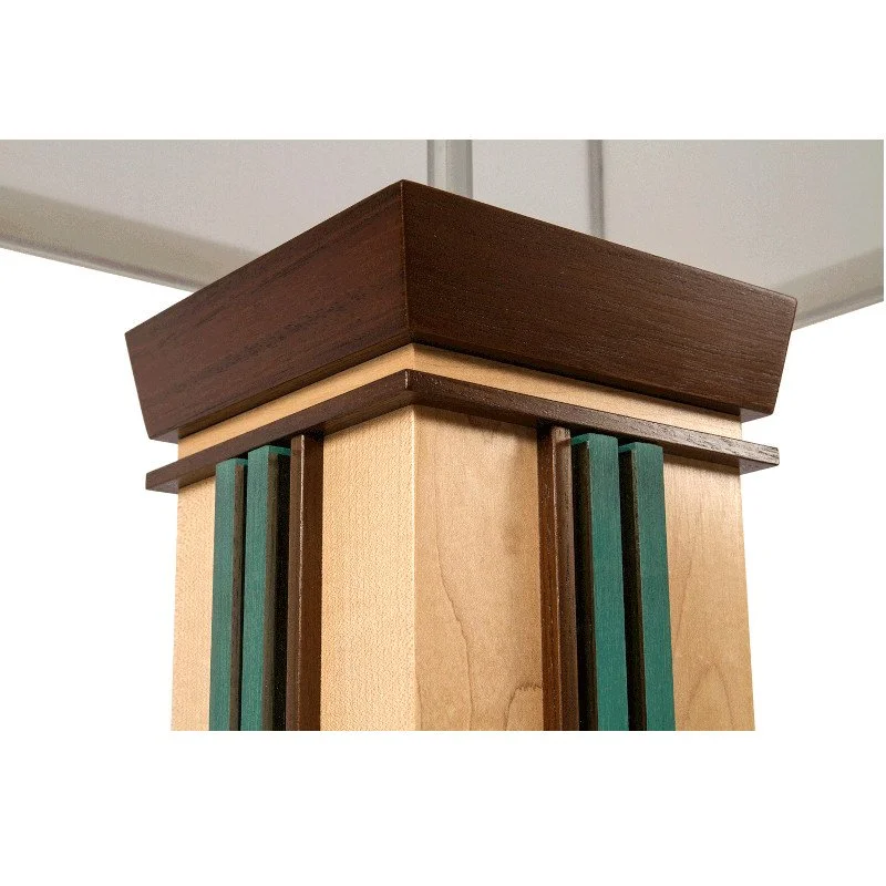 Close-up of a wooden lamp corner with a dark brown top, beige middle, and decorative vertical teal acrylic and dark brown accents.