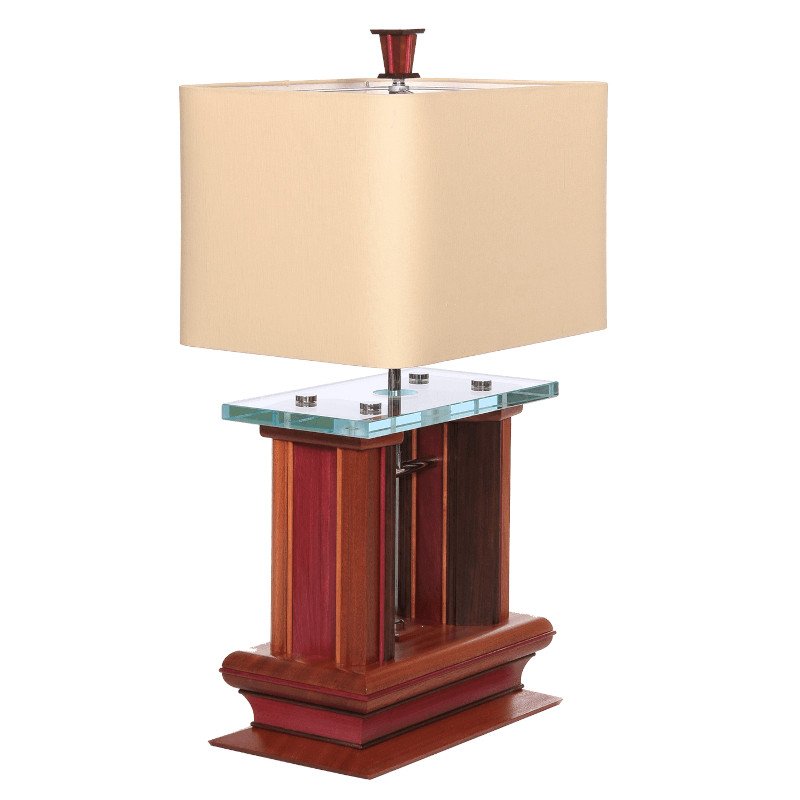 A table lamp with a beige rectangular fabric shade, a glass shelf, and a wooden base with a mix of red and brown tones.