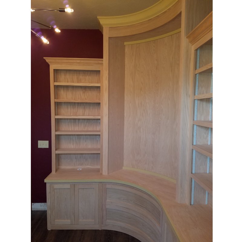 Wooden built-in shelves and cabinets in a room with dark red walls and a light-colored ceiling.
