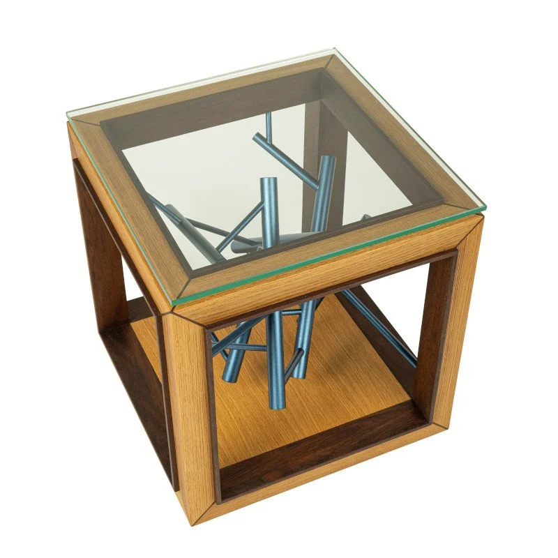A wooden side table with a glass top containing a modern sculpture of metallic rods arranged in an abstract formation.