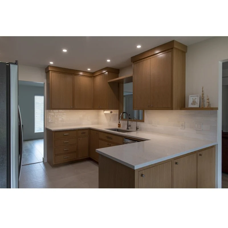 Kitchen with wooden cabinets, marble countertops, sink, and a window above the sink with decorations on the shelf.