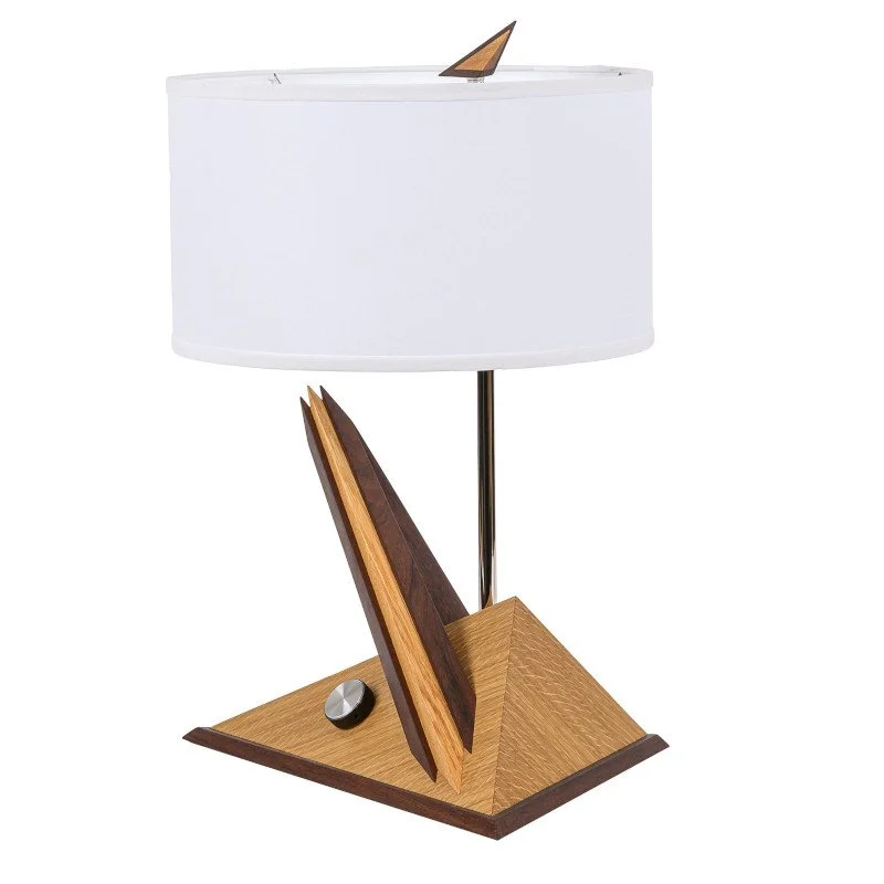 A modern table lamp with a wooden geometric base, a white fabric lampshade, and a small decorative wooden finial on top.