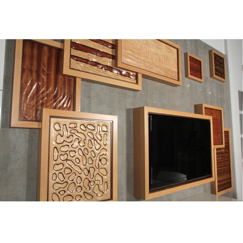 Display of various decorative wood panels and frames mounted on a wall, surrounding a black flat-screen television.