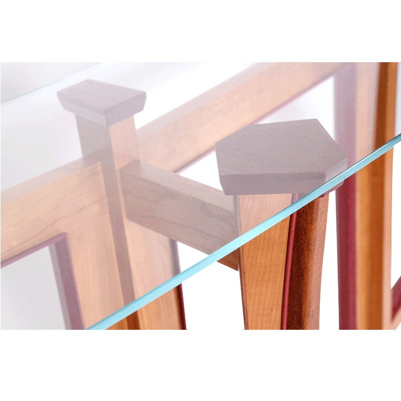 Close-up of a wooden table with a glass top, showing the reflection of the table's corner and supporting leg.