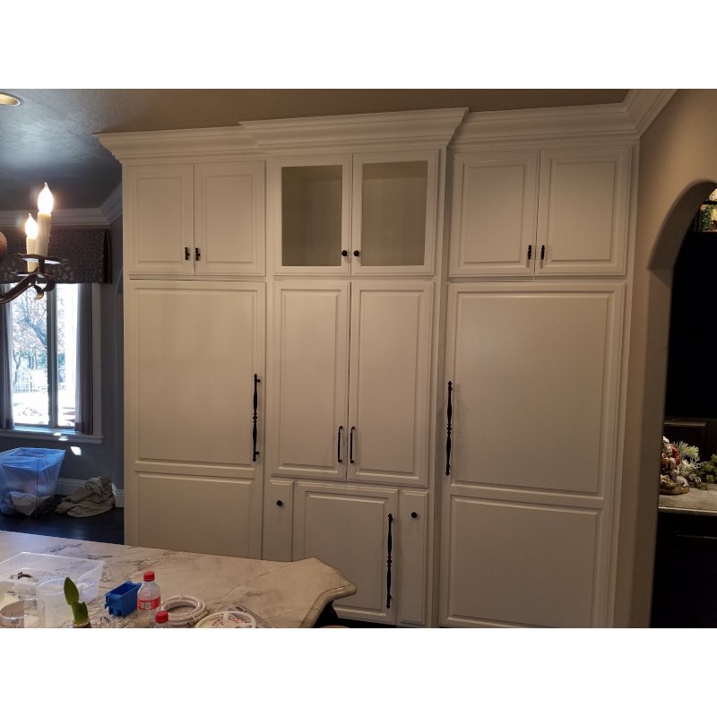 White built-in kitchen cabinets with black handles in a home kitchen.