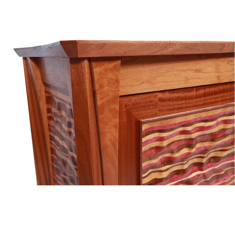 Close-up of a wooden furniture piece with detailed wood grain and carved decorative panels.