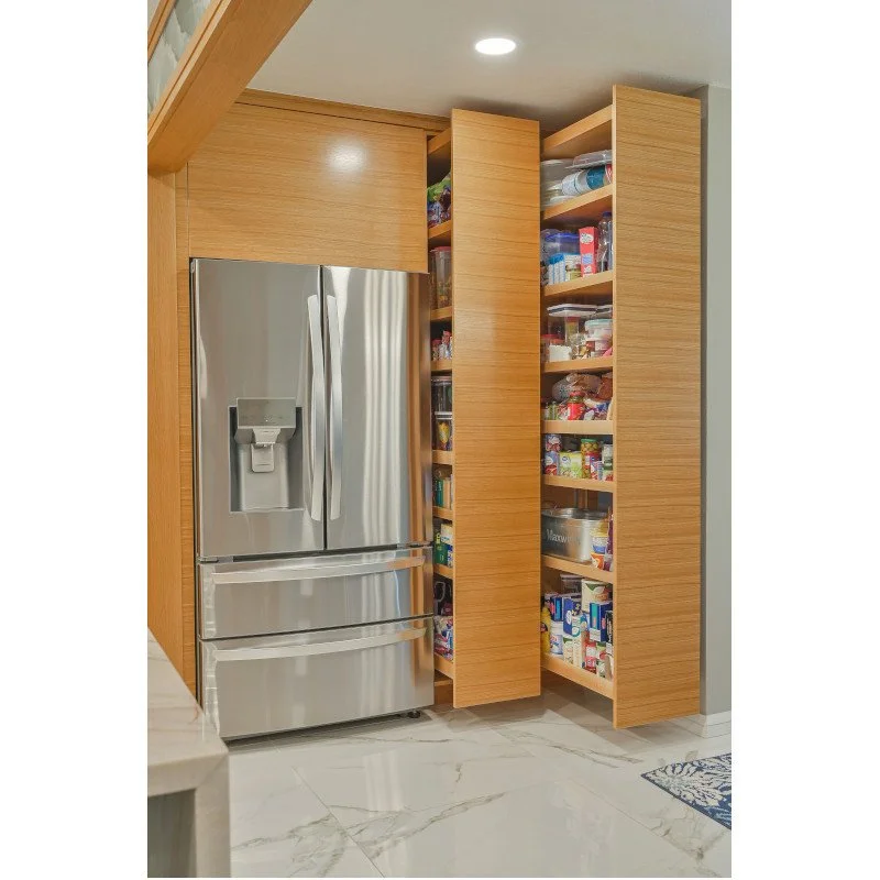 Stainless steel refrigerator with freezer drawers next to Fulterer wooden pantry shelves filled with various food items and packages.