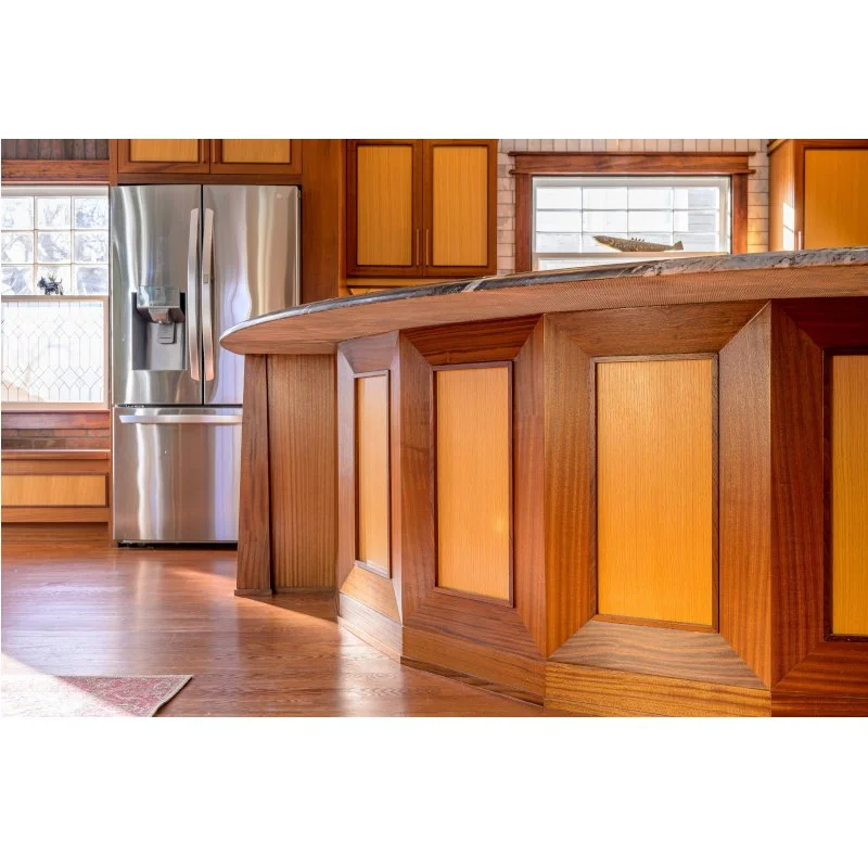 Wooden kitchen island with a granite countertop, stainless steel refrigerator, and wooden cabinets in the background.