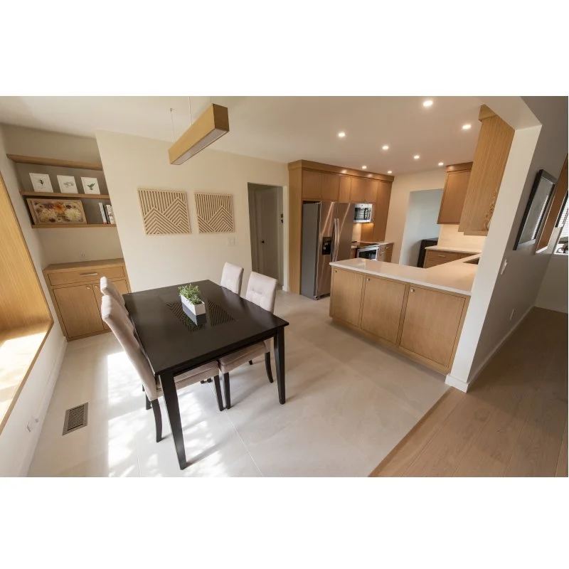 Modern kitchen and dining area with a dark wood dining table, beige upholstered chairs, and light wood kitchen cabinetry. There is a small potted plant on the table.
