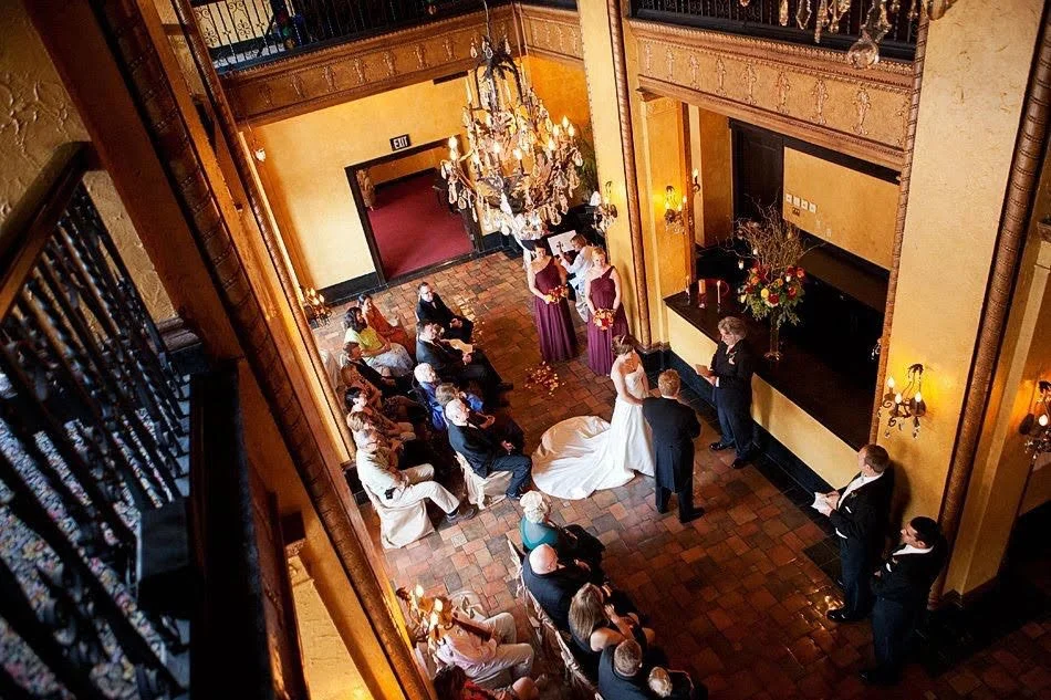 Gorgeous wedding in a historic location with a chandelier overhead. Rev George performing ceremony in front of Bride, Groom, and family