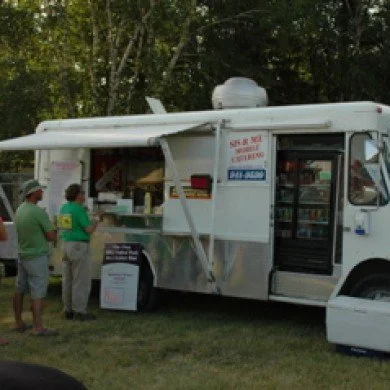People ordering food at a white food truck with a serving window outdoors