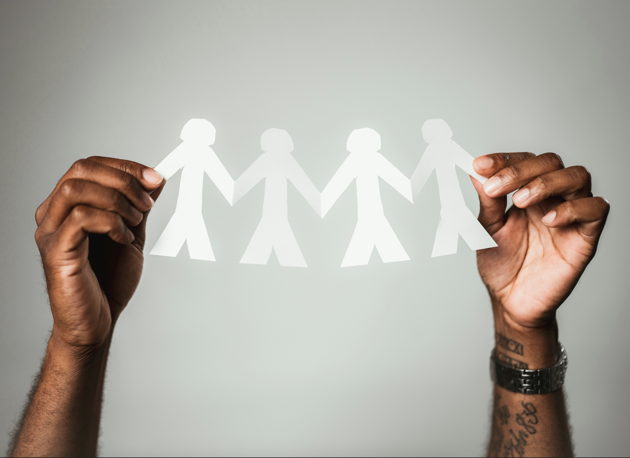 Person holding a paper paper chain cutout of people, symbolizing unity and togetherness.