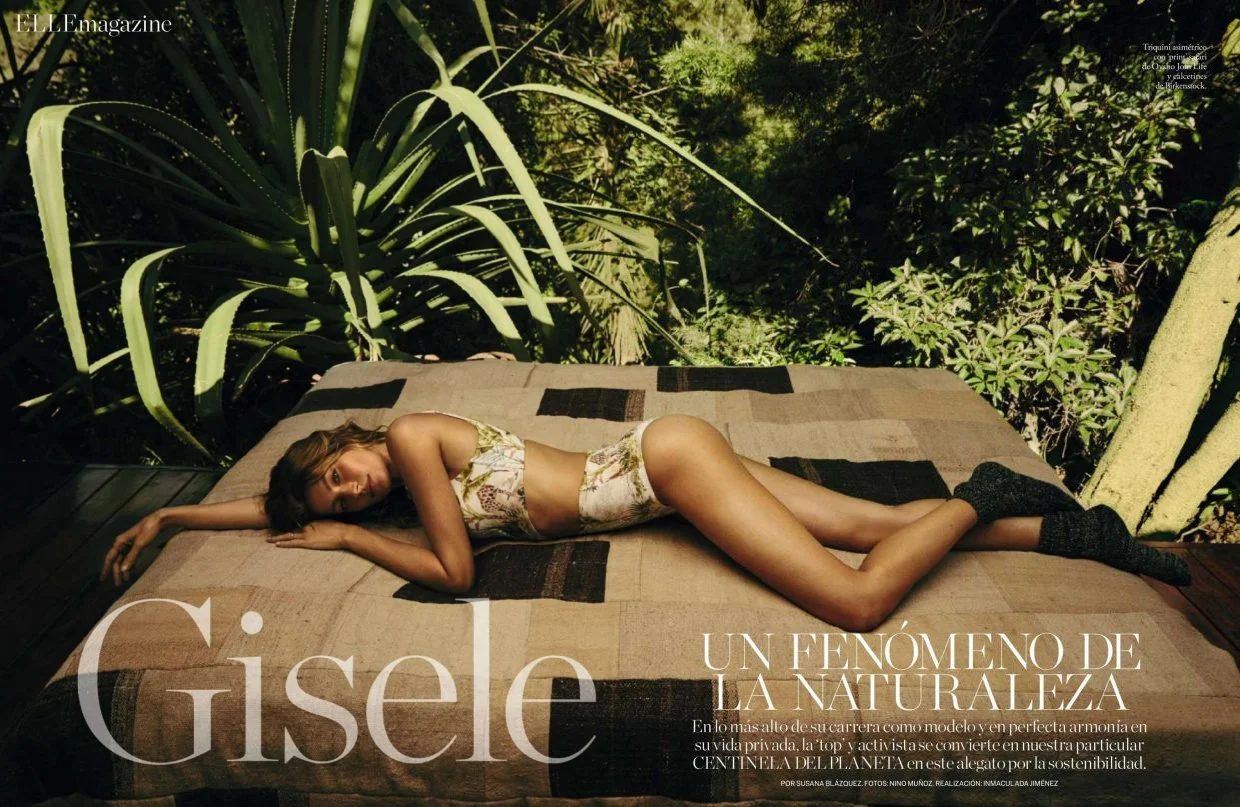 A woman lying on her side on a bed with brown and black sheets, surrounded by large green plants, and a sunny outdoor setting.