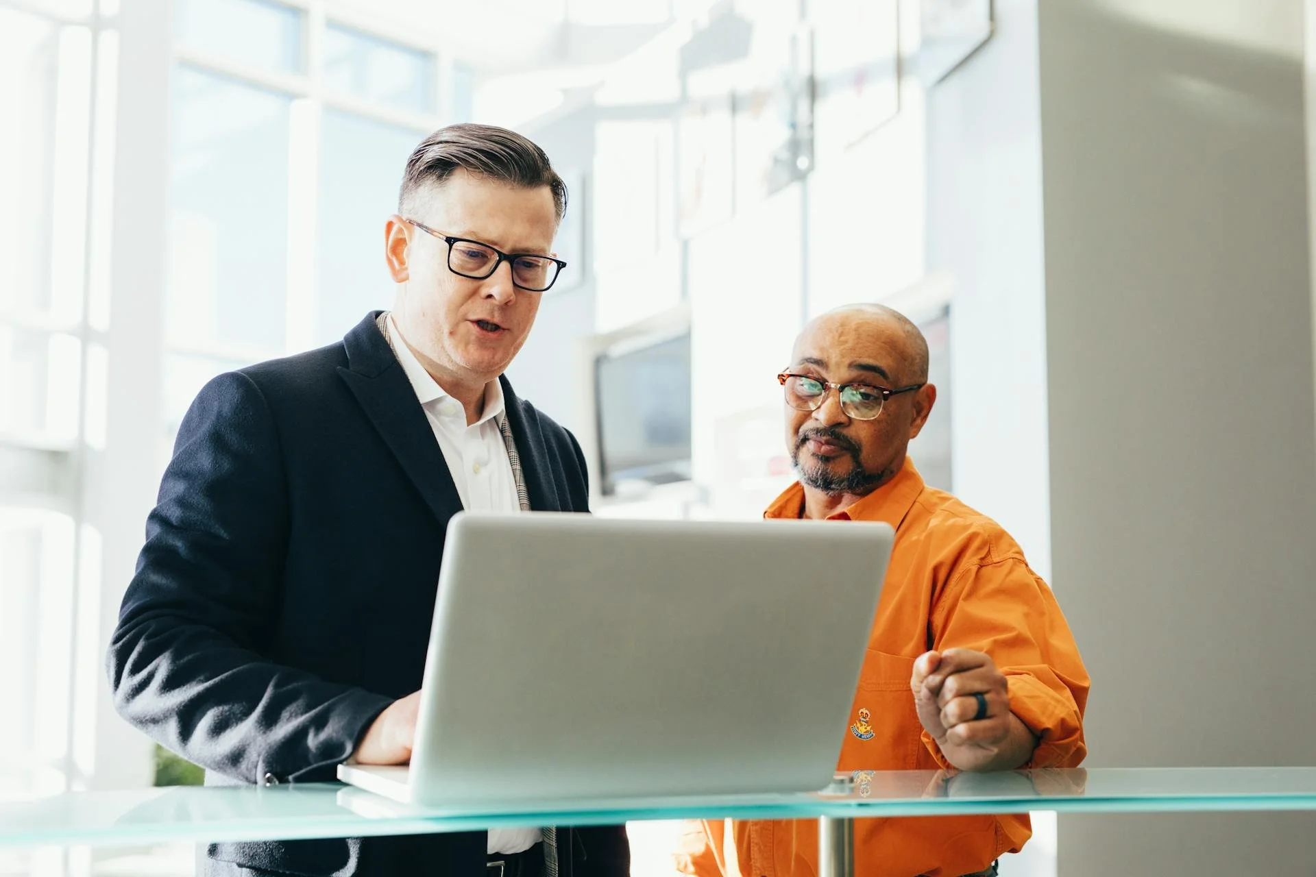 Two men looking at a laptop in a modern, brightly lit office.