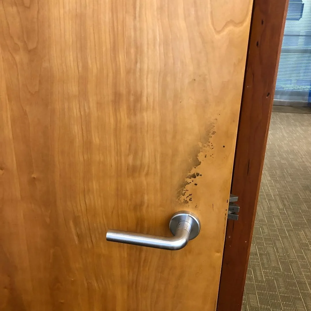 Wooden door with a silver door handle and visible water damage near the bottom