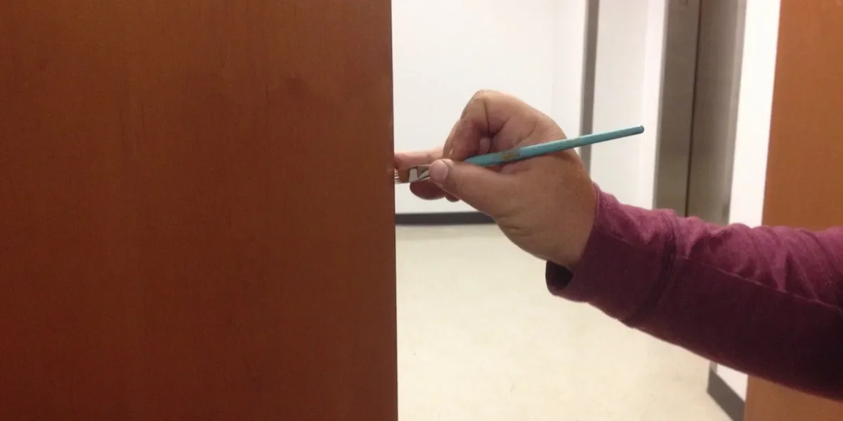 A person holding a paintbrush while painting a door.
