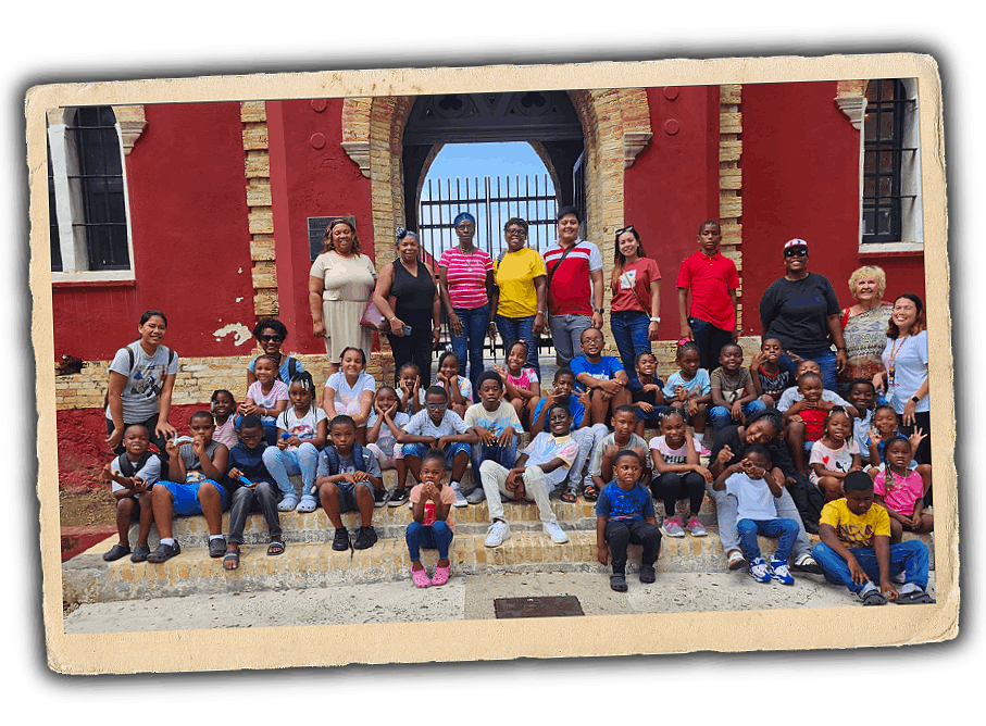 Group photo of children and adults in front of a red brick building with an arched entrance.