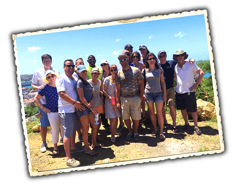 Group of people outdoors on a sunny day, standing together for a photo with a natural landscape behind them.