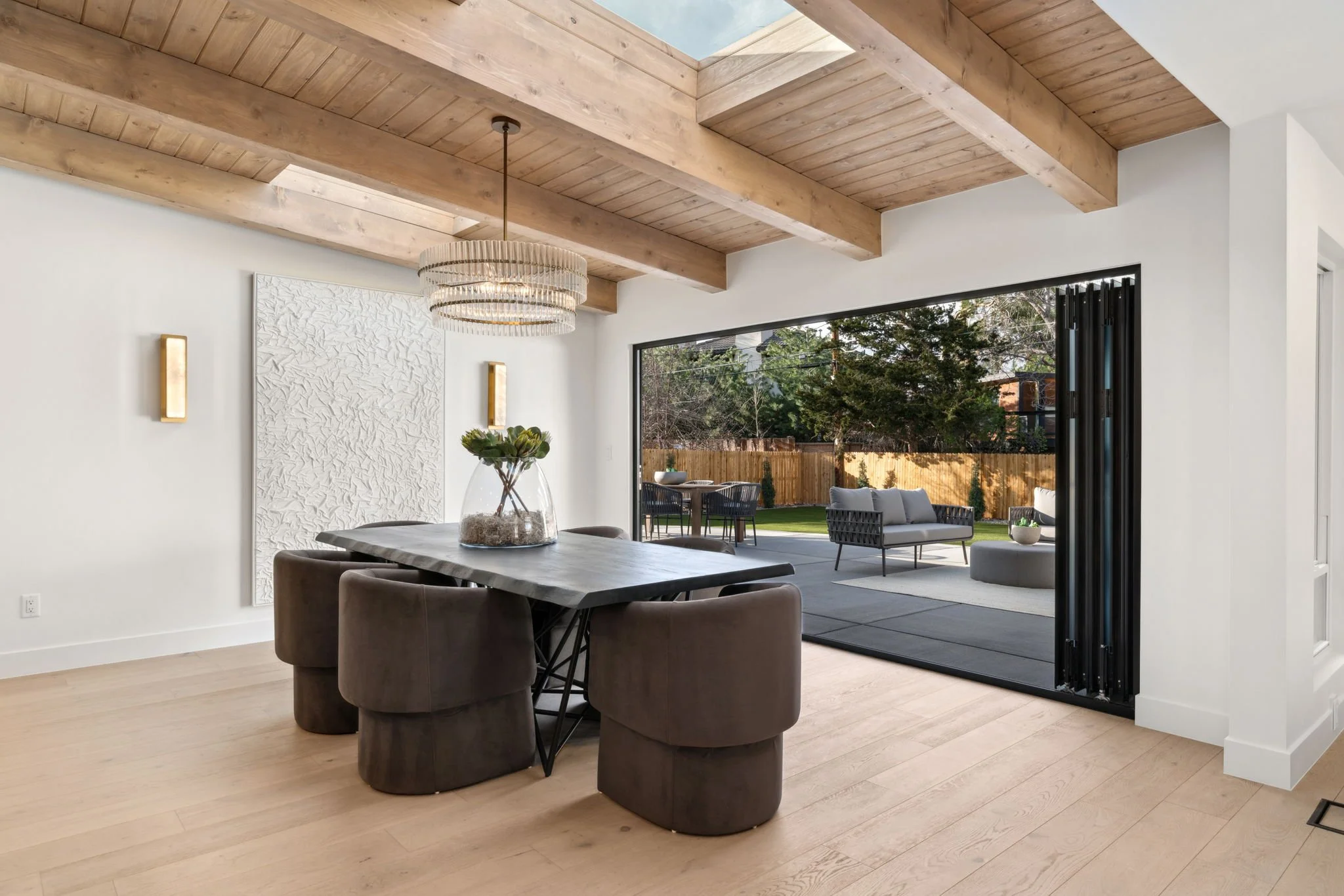 Modern dining room with vaulted ceilings with wood beams and a collapsible patio door in Cherry Creek, Colorado