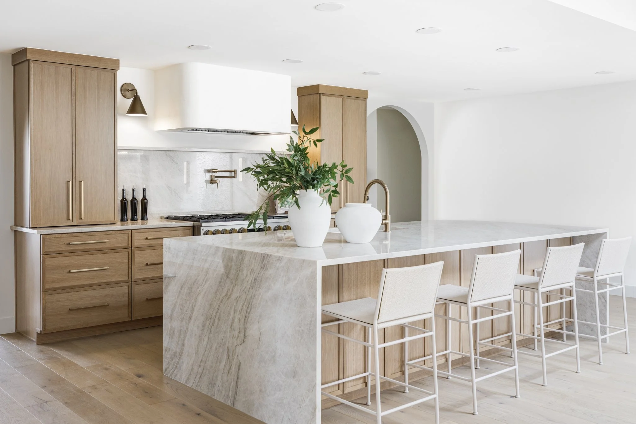 Modern luxury kitchen featuring a large waterfall island, custom cabinetry, and premium finishes.