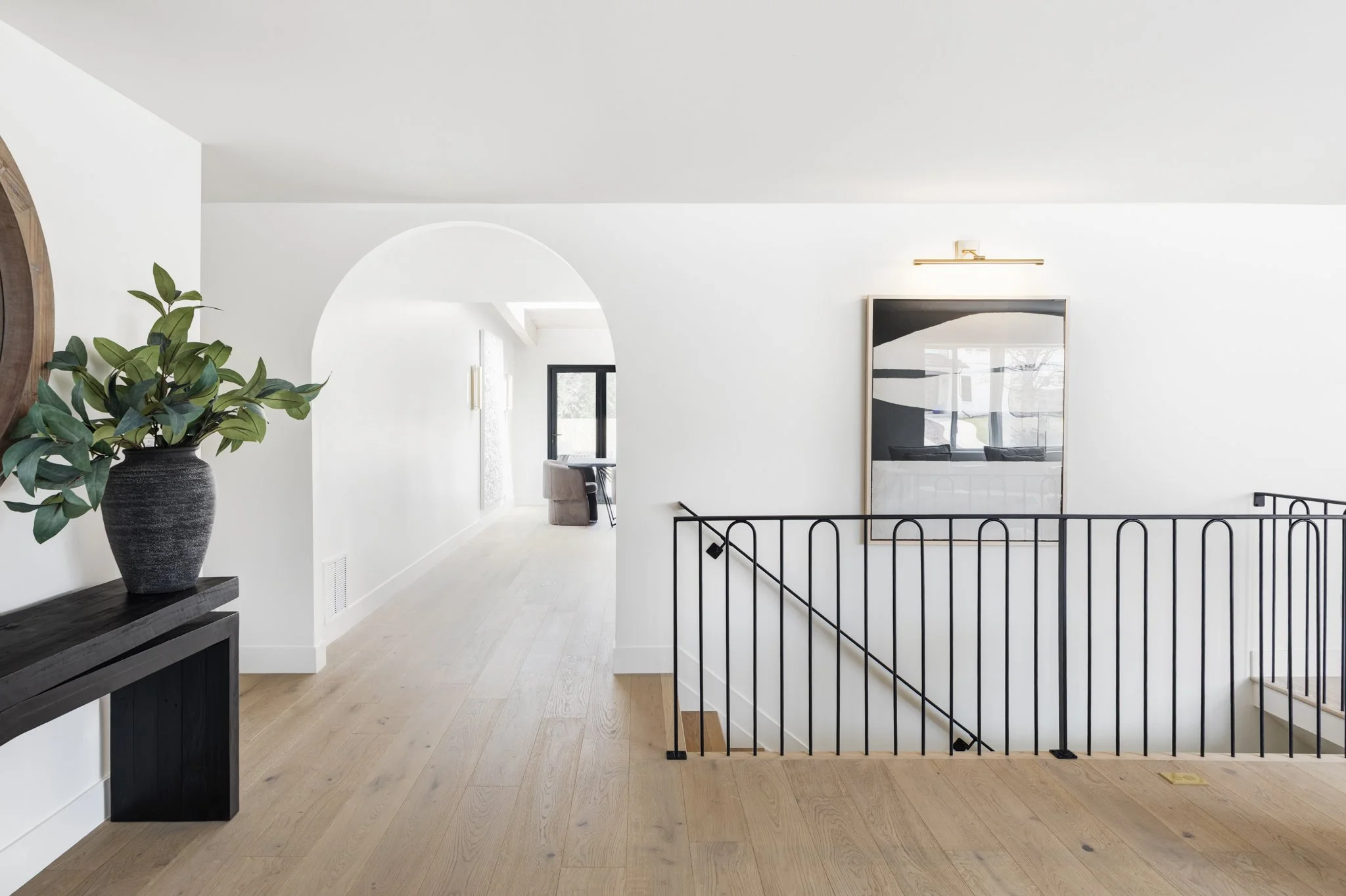 Modern luxury home entryway with hardwood floors, arched hallway, and contemporary staircase.