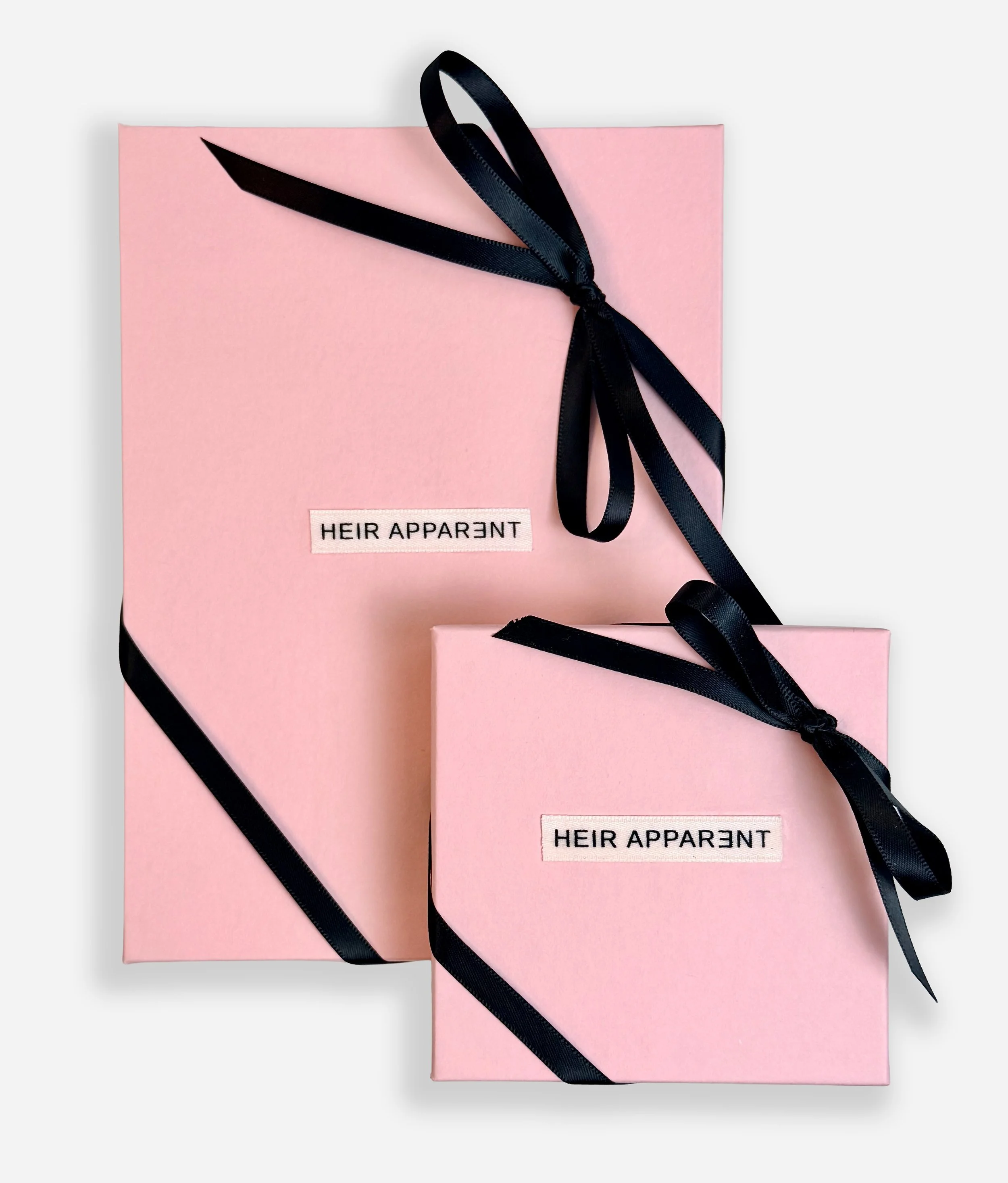 Heir Apparent Jewelry pink gift boxes with black ribbon and branded packaging.