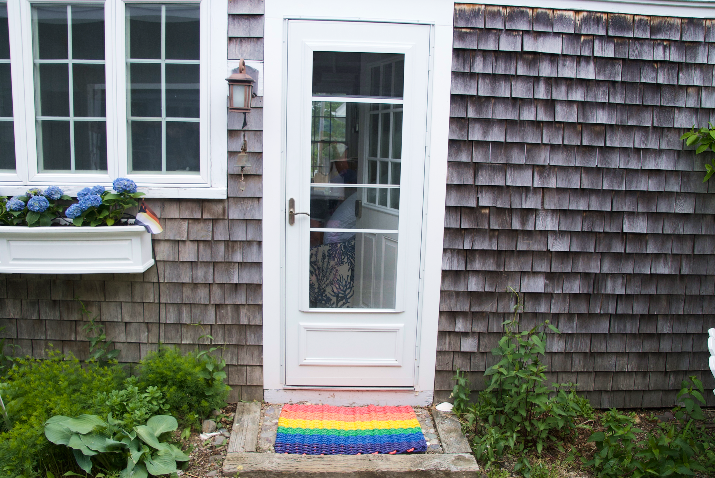 Front door of Little Gay Inn showing a rainbow pride welcome mat.