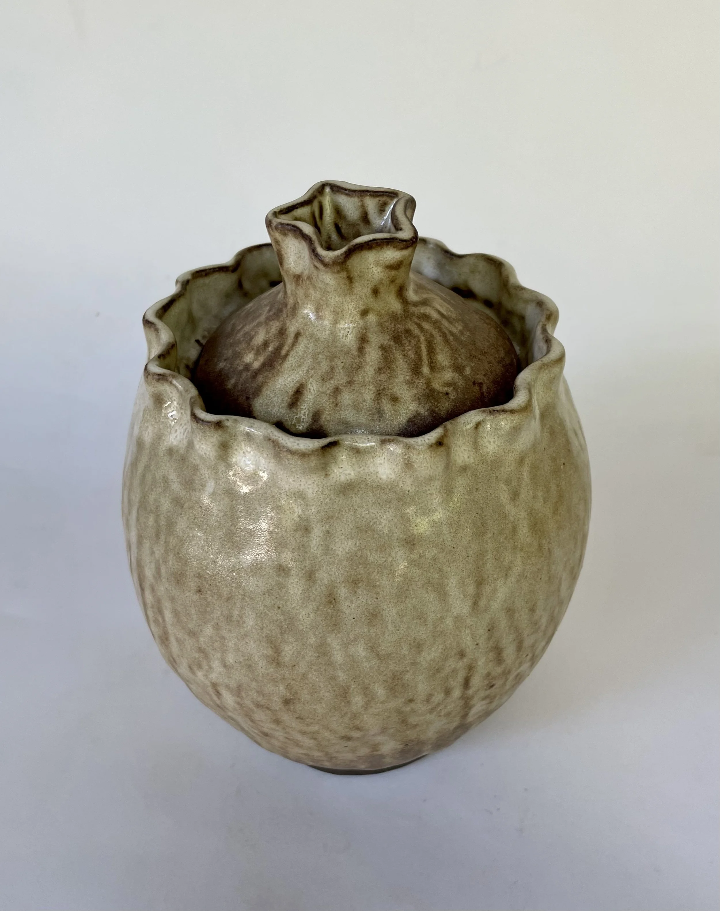 A ceramic vase with a ruffled top and a rounded body, glazed in a beige and brown mottled pattern.