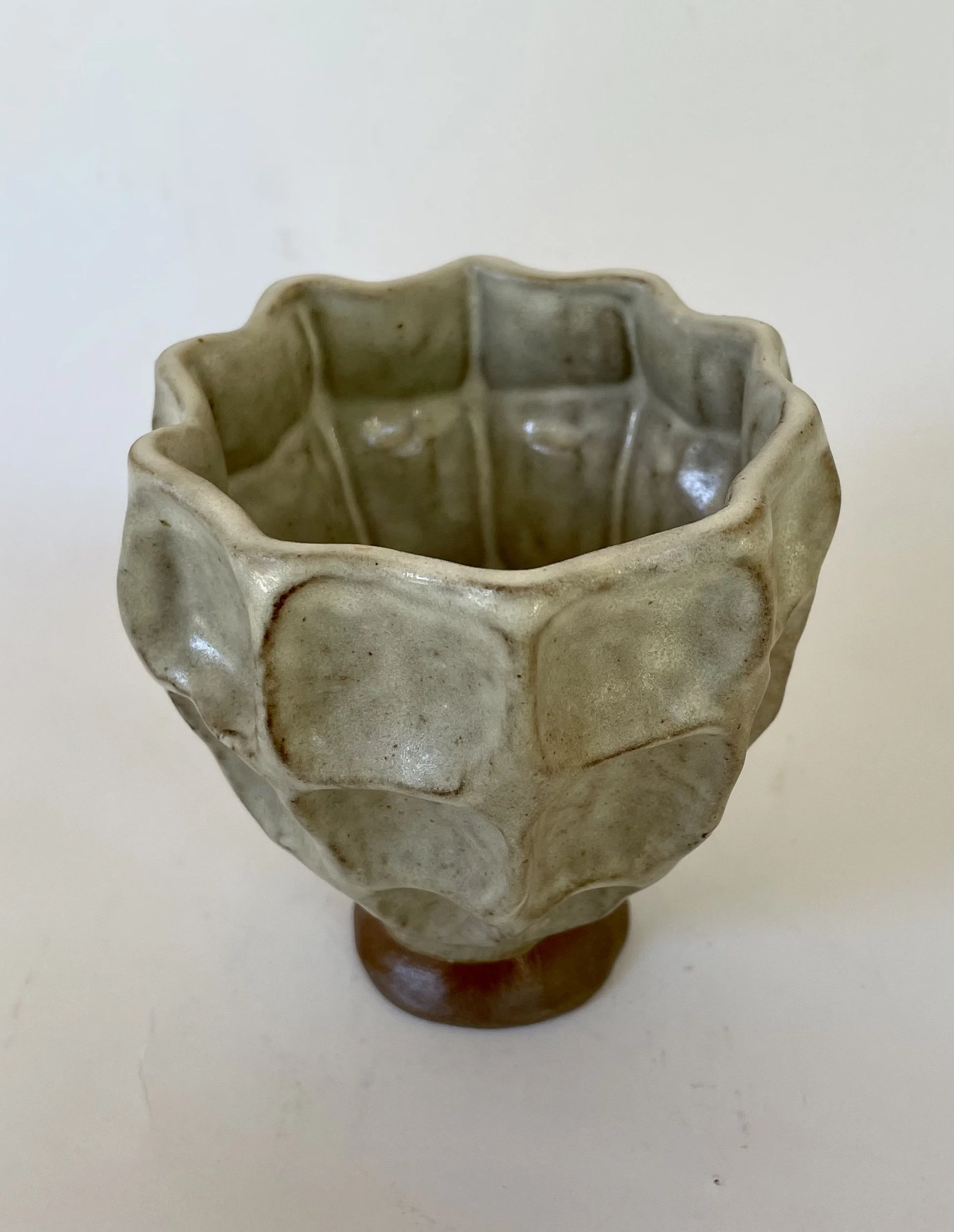 Ceramic decorative vase with a textured, geometric pattern and a small, round base.