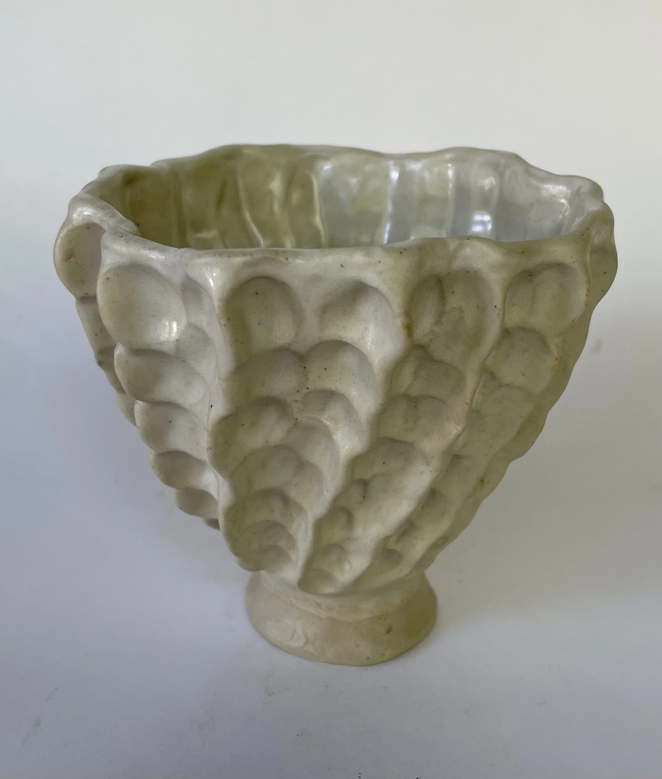 A ceramic bowl with a textured, bubble-like surface design, in a beige or light cream color.