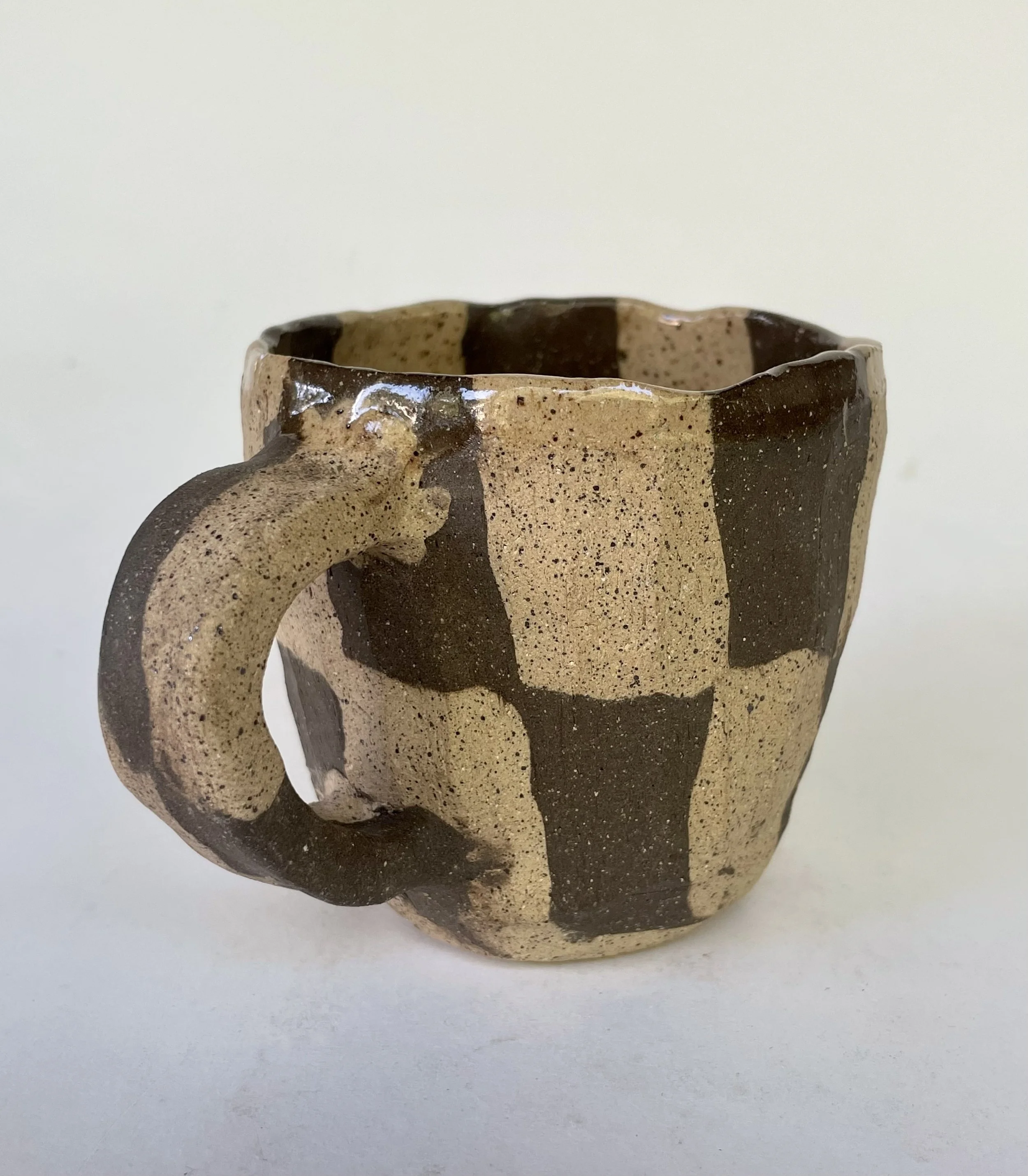 A ceramic mug with a textured surface, featuring large beige and dark brown irregular stripes.