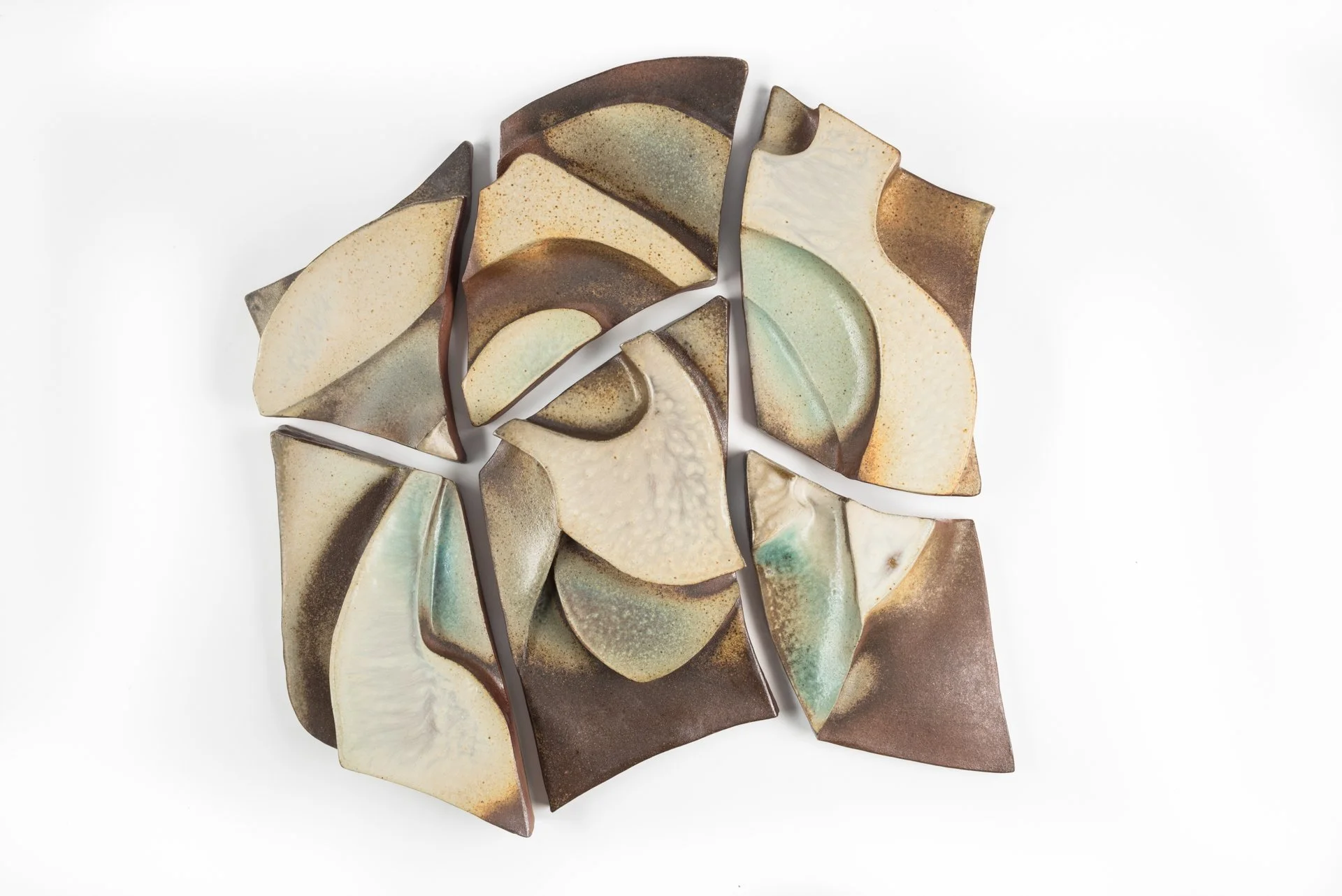 Abstract ceramic wall art with 6 pieces arranged on a white background, exhibiting a variety of earthy tones and textures.