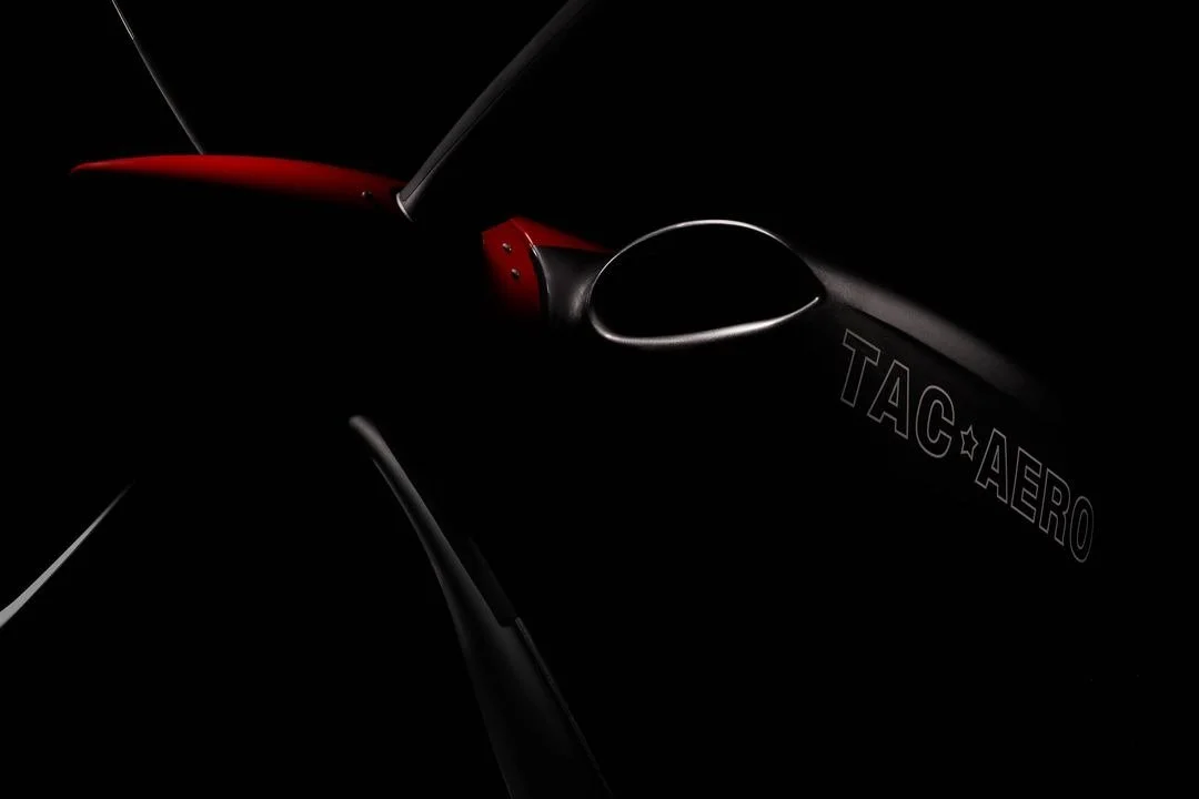 A close-up of a black and red aircraft with the text "TAC AERO" on its side, mostly obscured by darkness.
