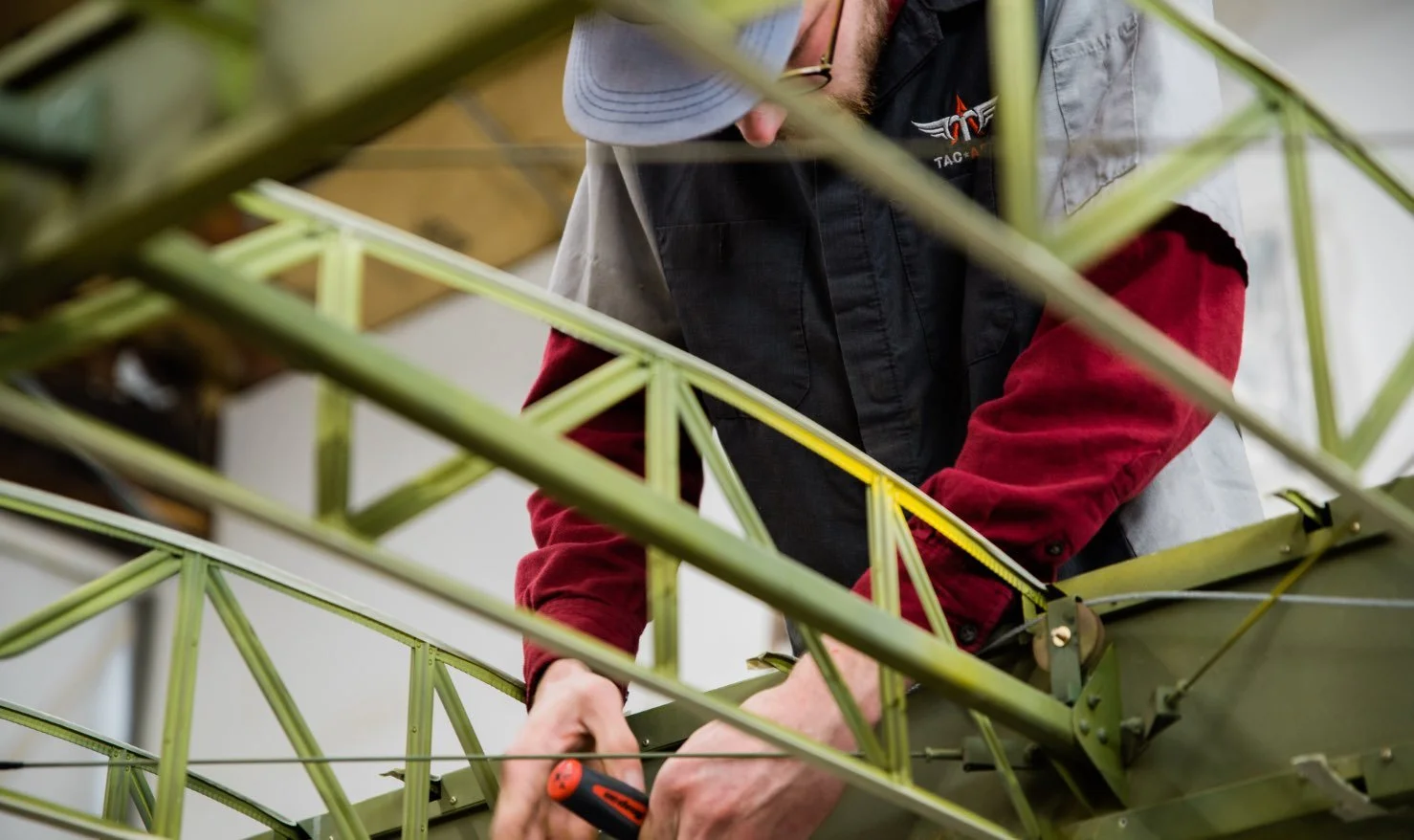 A person working on a green metal structure, using a screwdriver.