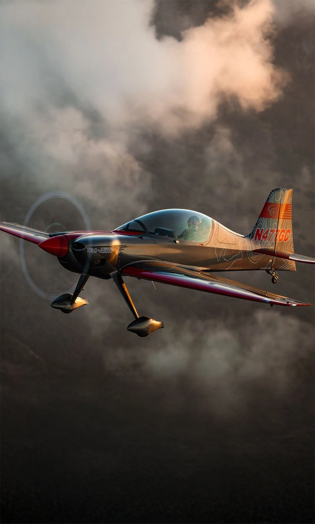 An airplane flying through a cloudy sky with a pilot visible inside the cockpit.