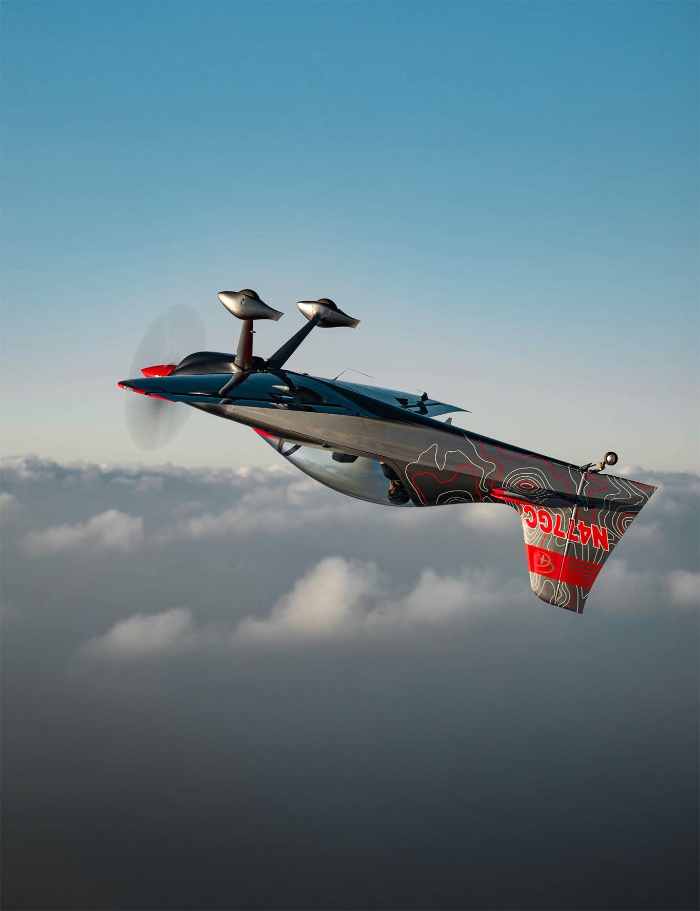 A futuristic aircraft flying high above the clouds with a sleek design, black and red color scheme, and the word N477CC on its tail.
