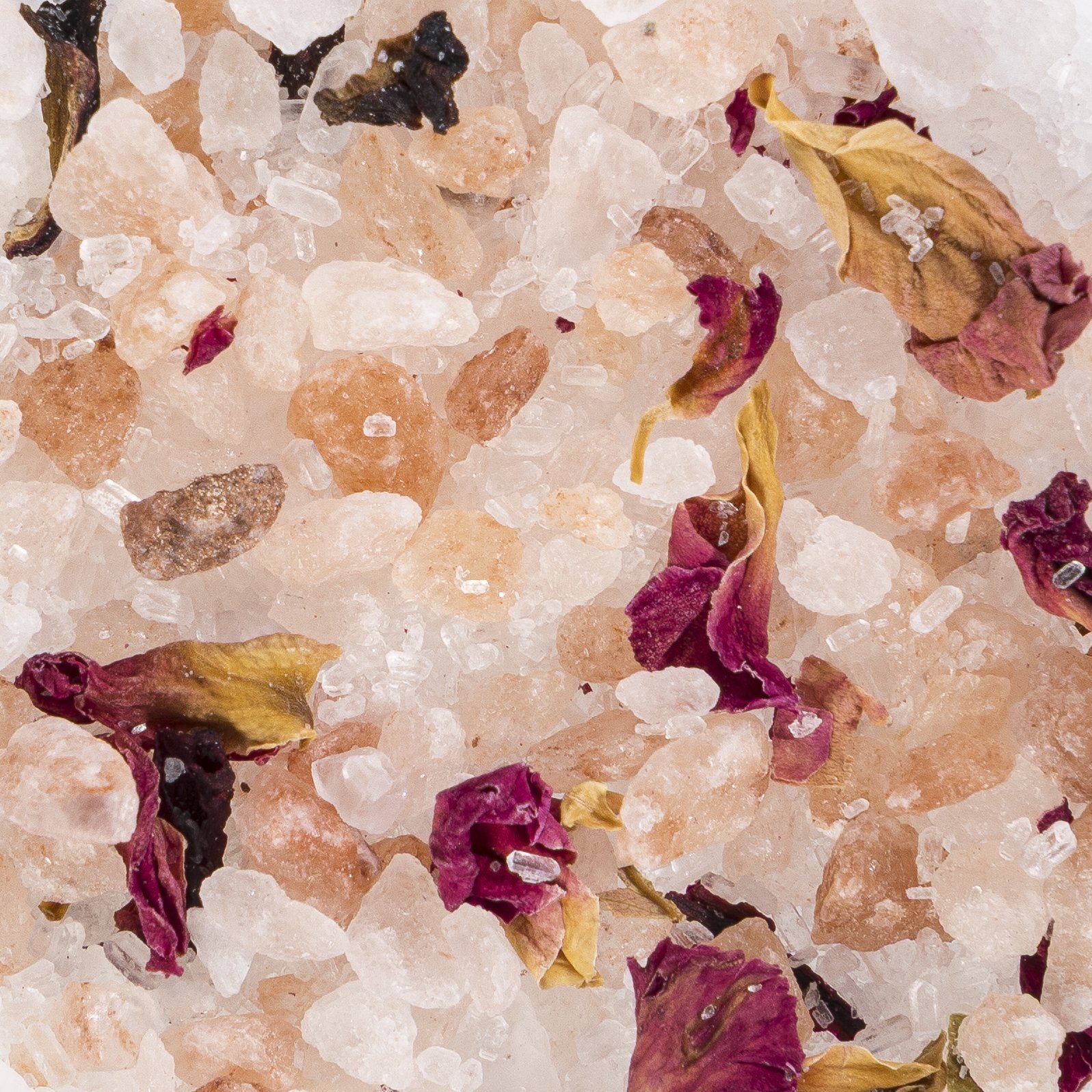 Close-up of Himalayan pink salt crystals with dried rose petals scattered on top.
