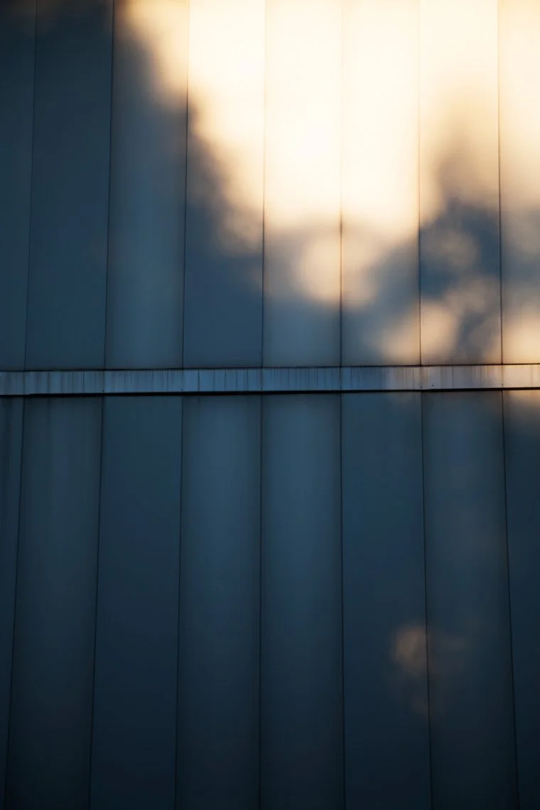 Reflection of the sky with clouds on a modern metallic building facade at sunset.