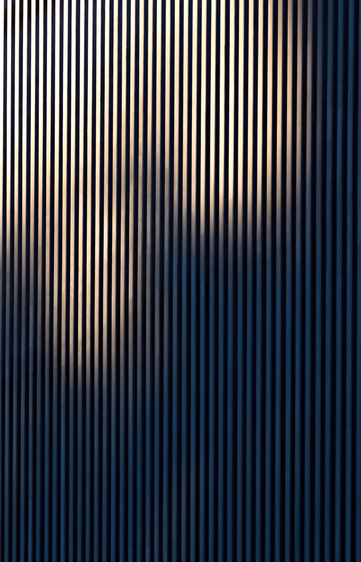Close-up of a textured black surface with vertical ridges, partially illuminated.