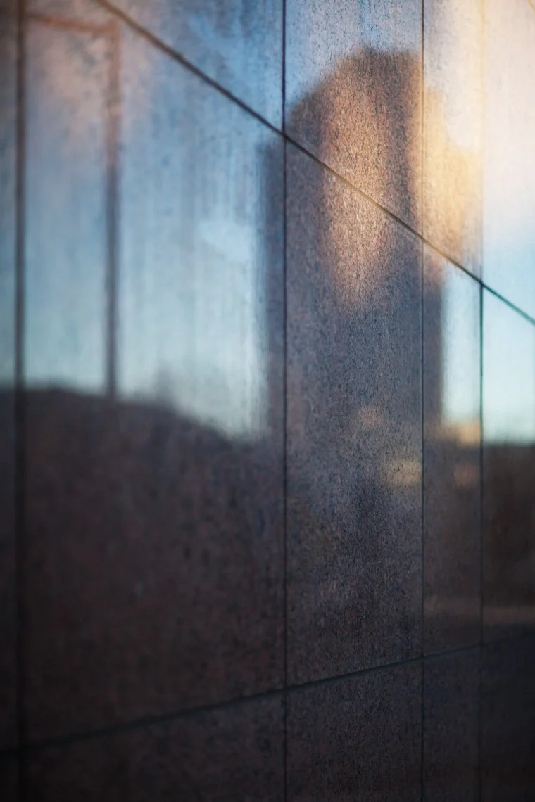 Close-up of a tiled wall reflecting the shadow of a person and sunlight.