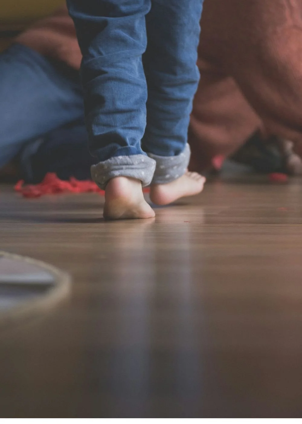A small child walking barefoot while mother is cleaning up, overwhelmed mother.