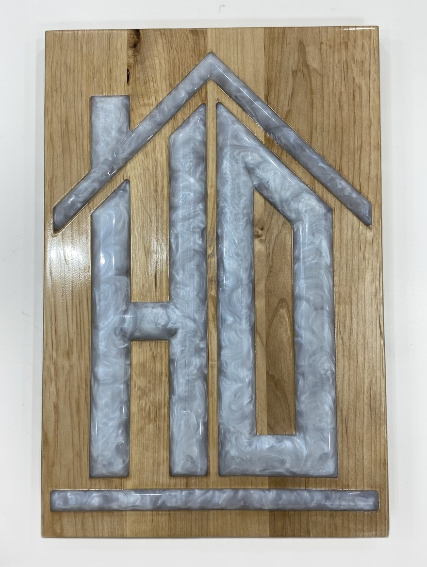 Decorative wooden sign with metal overlay design resembling a house with a roof, walls, and a foundation.