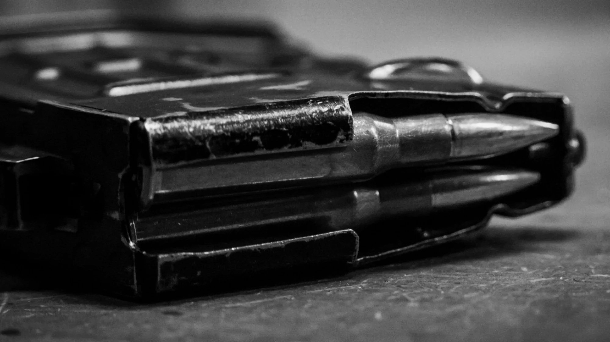 Metal AR-15 magazine on wooden surface, black and white close-up image