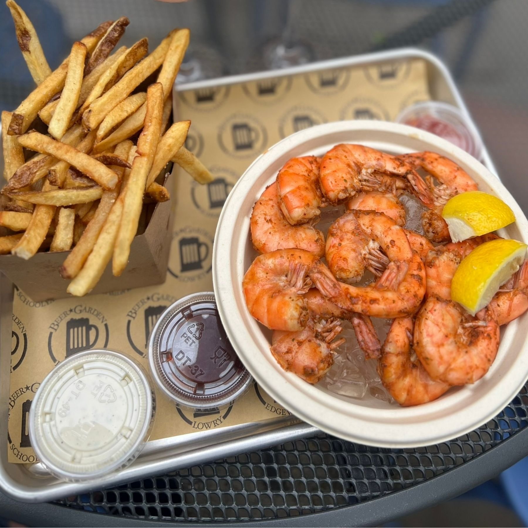 Chilled pull and eat shrimp and fries plated outside at a beer garden