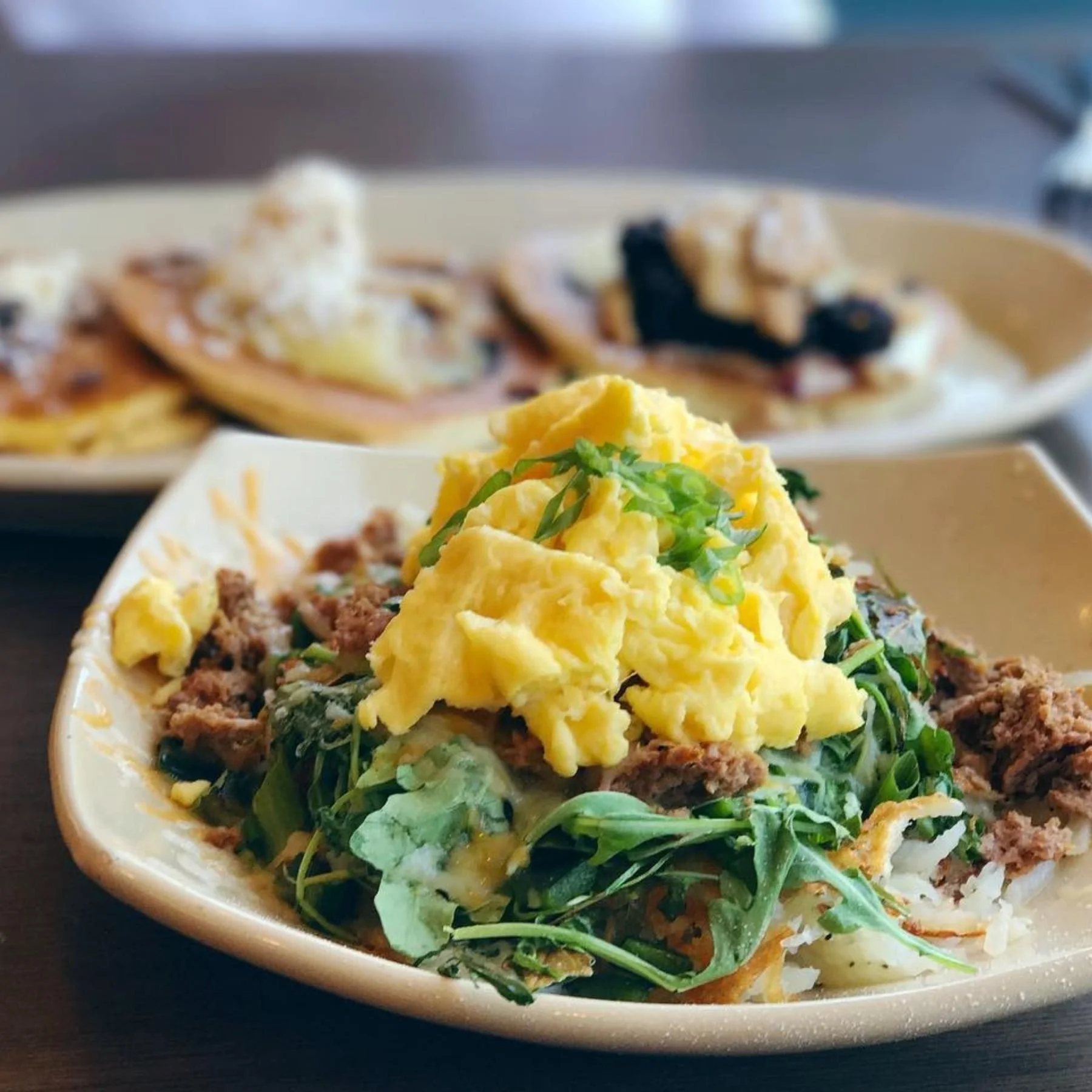 Brunch eggs served with a flight of pancakes at a casual breakfast restaurant in Denver