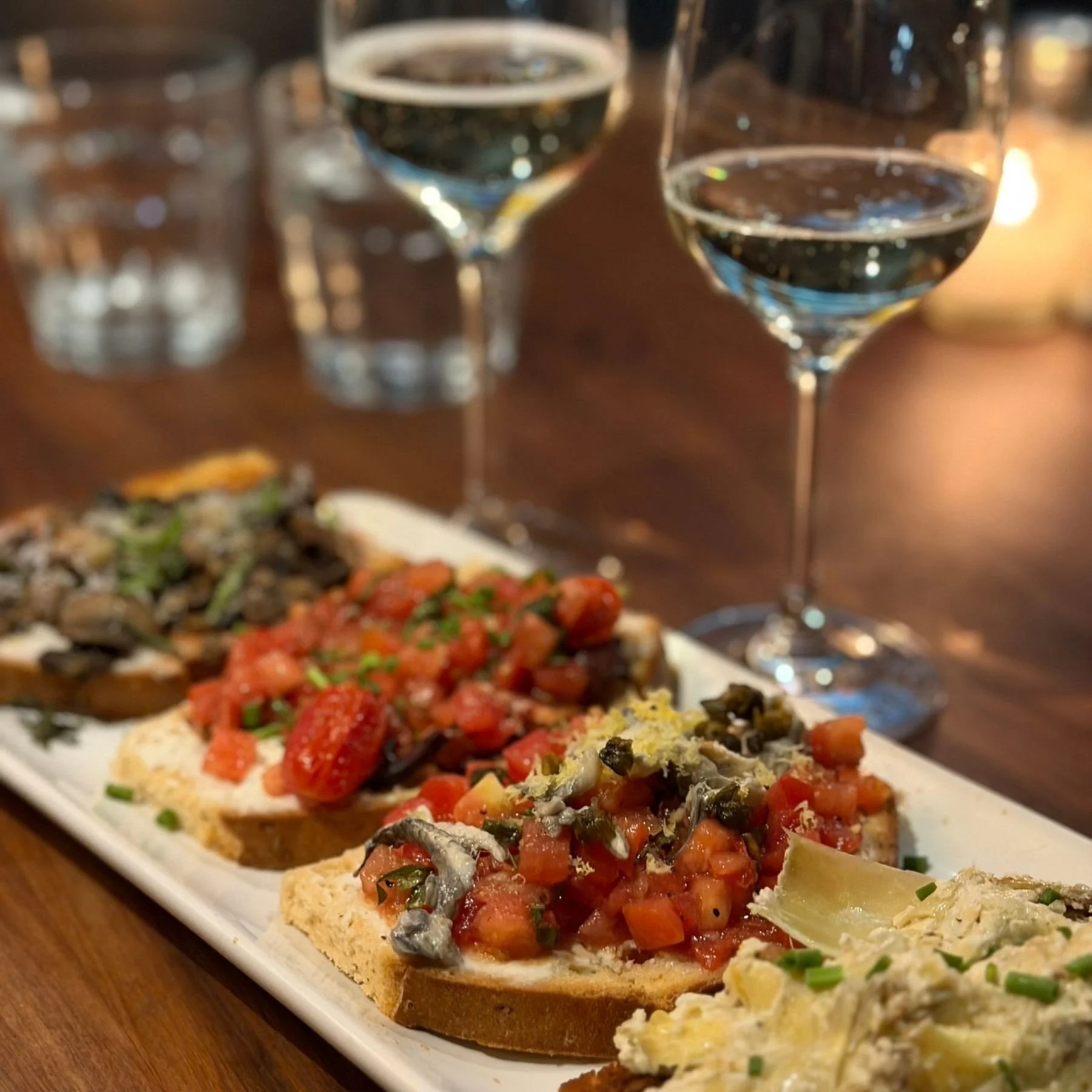 Bruschetta appetizer photographed with glass of verde wine during late night happy hour in Denver at Postinos