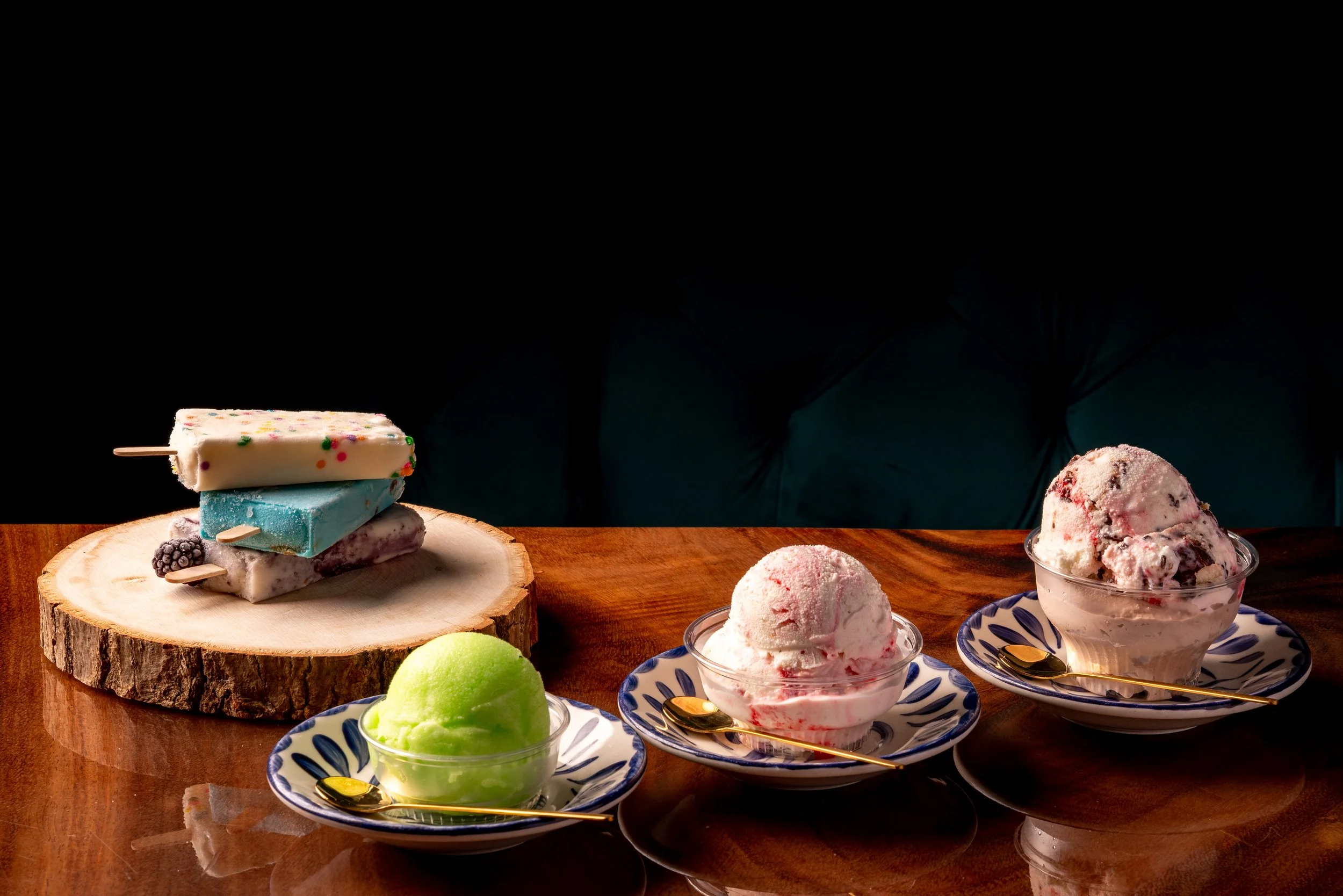 Various ice cream and popsicle desserts on a wooden table with a black background.