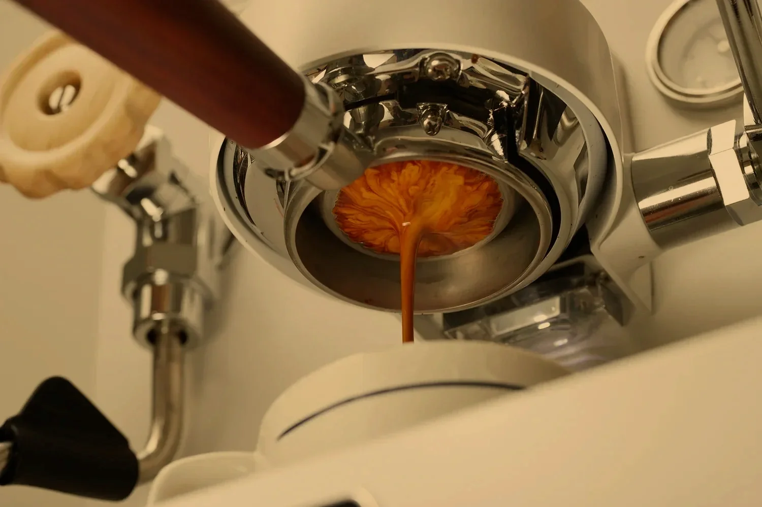 A coffee roasting machine pouring roasted coffee beans onto a cooling tray, with the coffee beans having a rich, dark color.