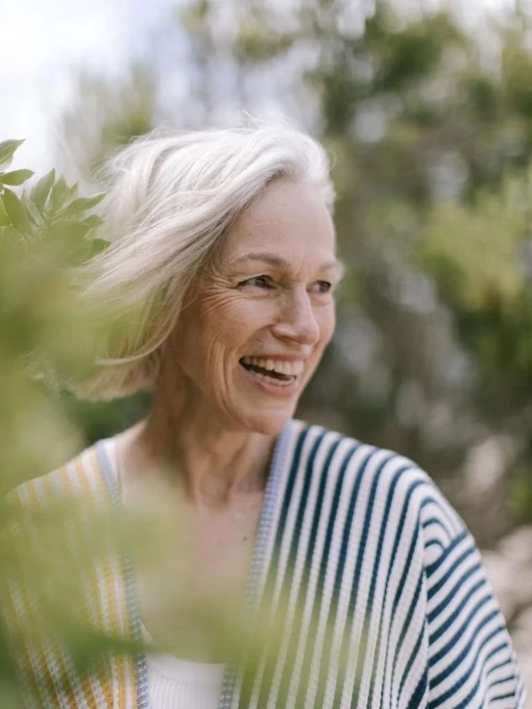 Smiling elderly woman outdoors with gray hair and striped shirt