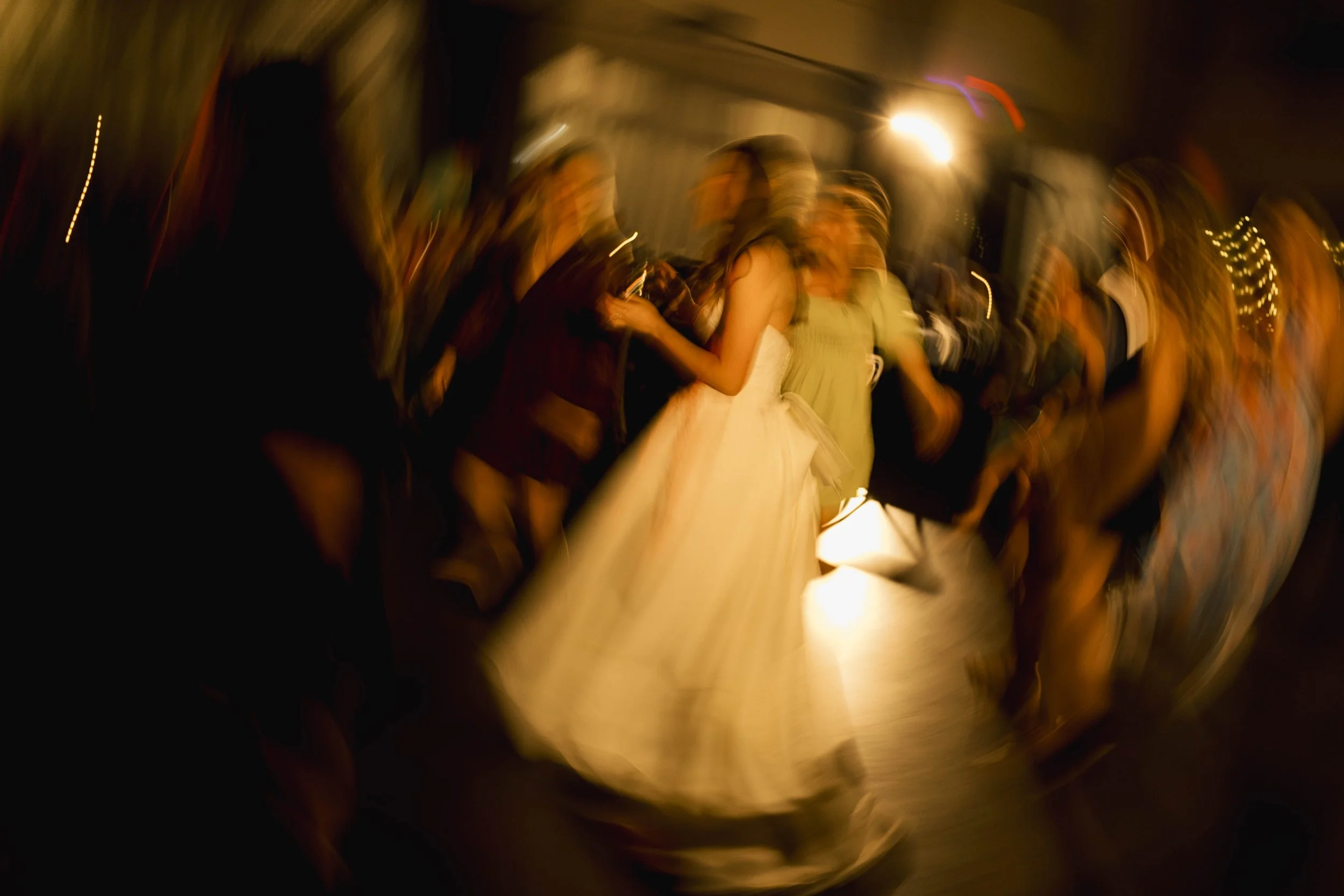 People dancing at a night event with blurred motion and warm lighting.